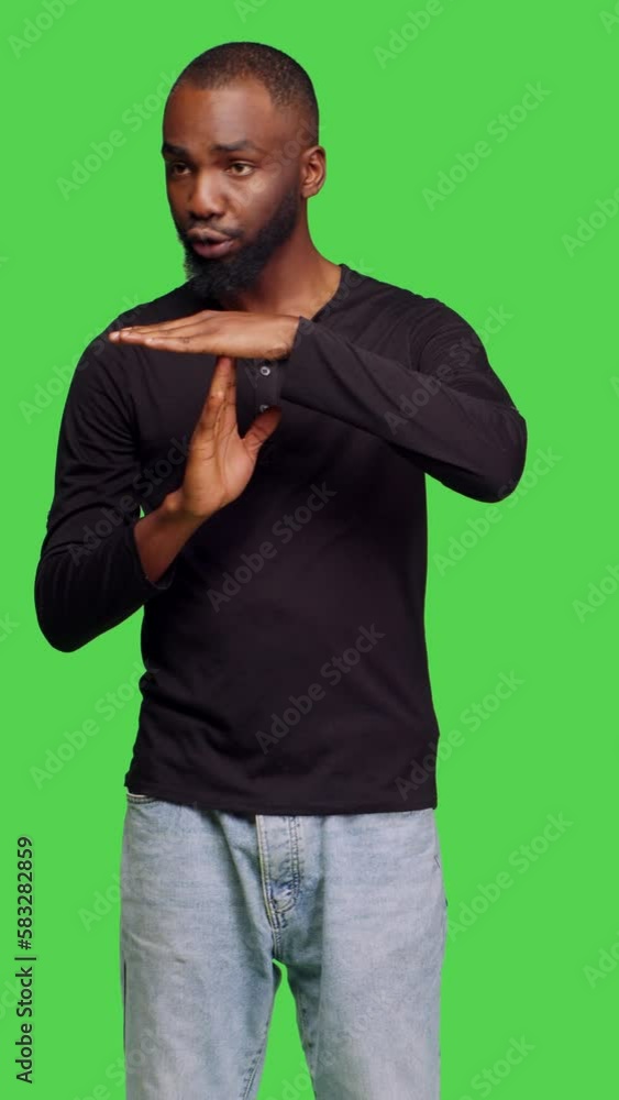 Vertical video: Front view of confident casual man expressing timeout gesture in studio, feeling displeased and showing pause or break symbol. Male model in denial doing rejection and refusal sign on Vertical video: Front view of confident casual man expressing timeout gesture in studio, feeling displeased and showing pause or break symbol. Male model in denial doing rejection and refusal sign on
