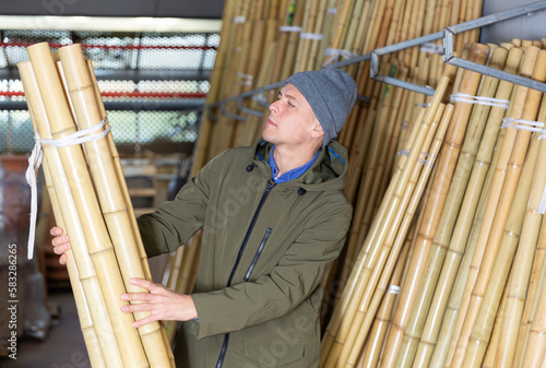 Man chooses bamboo sticks in a hardware store warehouse