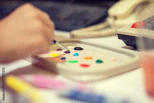 Close-up de mano de niño mojando el pincel con témperas de colores