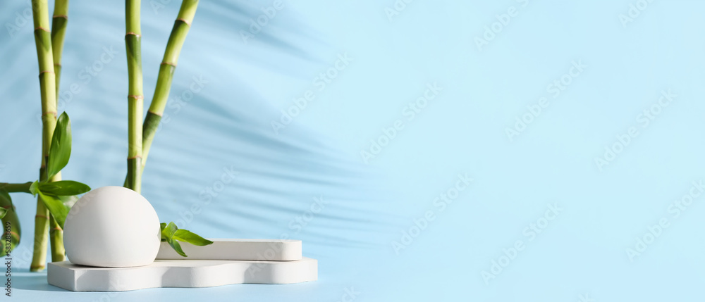 Empty podiums with green bamboo branches on light blue background with space for text