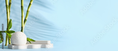 Empty podiums with green bamboo branches on light blue background with space for text
