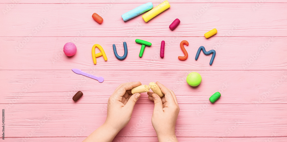 Child's hands with plasticine and word AUTISM on pink wooden background - obrazy, fototapety, plakaty 