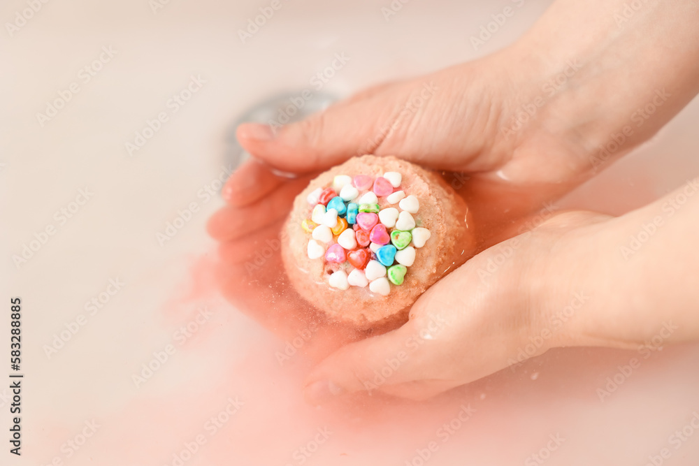 Woman putting bath bomb into water in room, closeup Woman putting bath bomb into water in room, closeup