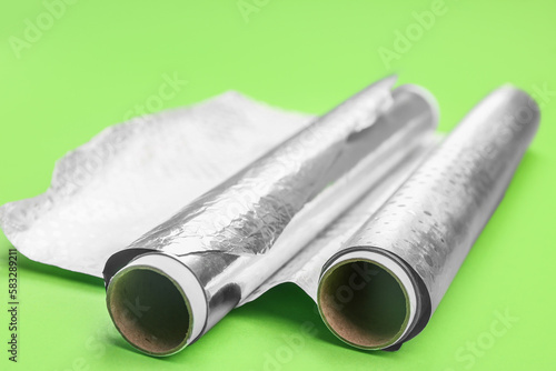 Rolls of aluminium foil on green background  closeup