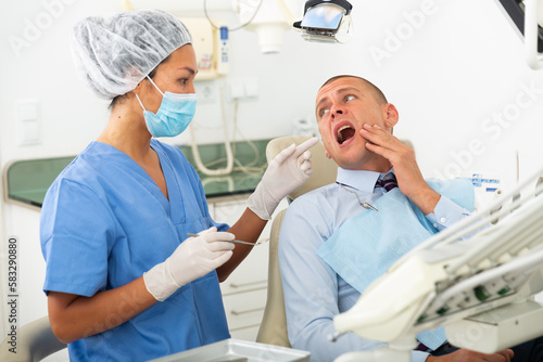 Man complains to the doctor about toothache at the dentist appointment