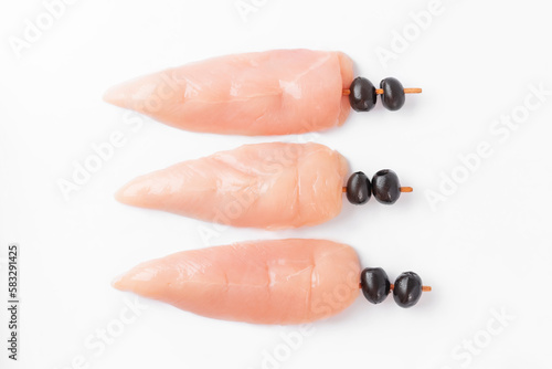 Raw uncooked Chicken meat, kebab on skewers on a white background .skewers of raw meat and vegetables.raw chicken inner on skewers with olives on a white background. photo