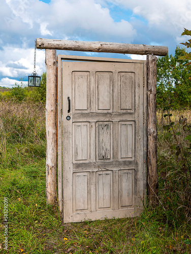 Wooden door without a house the middle of field. Old doorway that leads to nowhere. Concept of mystery portal