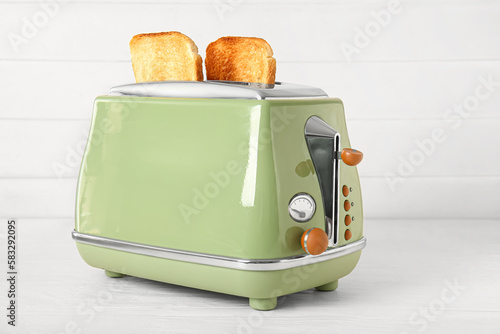 Modern toaster with crispy bread slices on white table