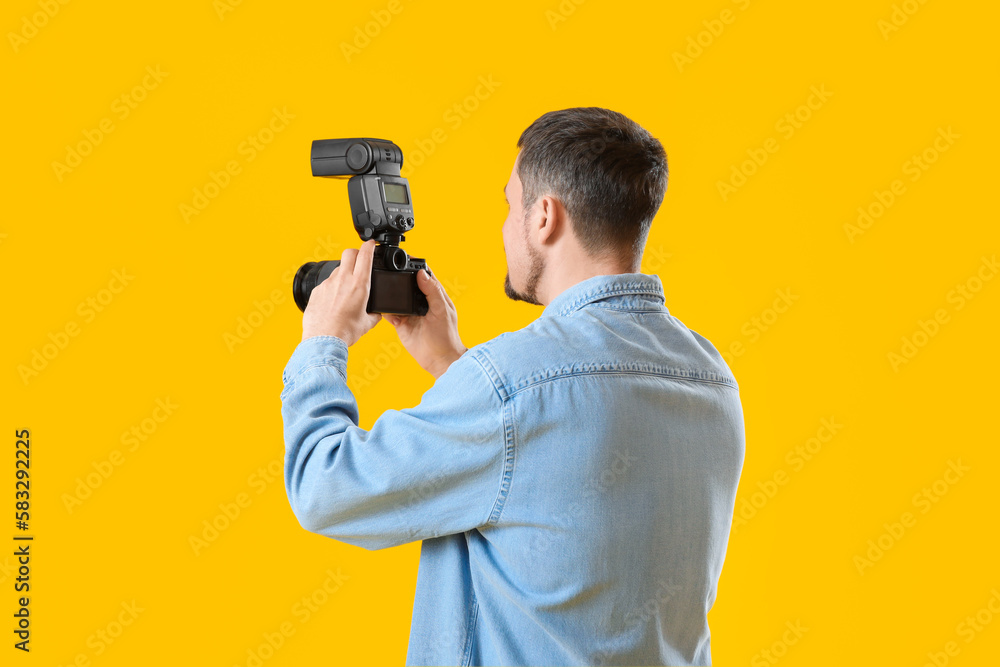 Male photographer with professional camera on yellow background Male photographer with professional camera on yellow background