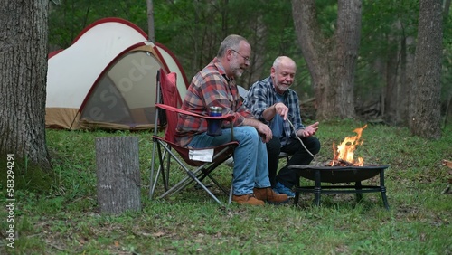 Closeup of two gay men in front of campfire laughing and smiling celebrating pride. © Robert Peak
