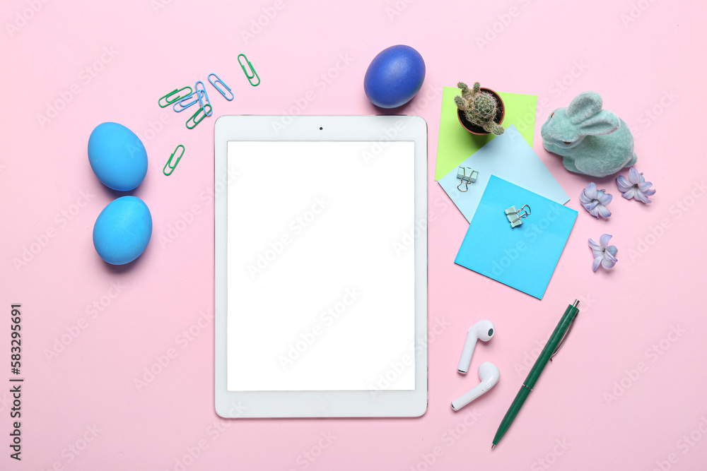 Tablet computer with office stationery, Easter eggs, rabbit and flowers on pink background Tablet computer with office stationery, Easter eggs, rabbit and flowers on pink background