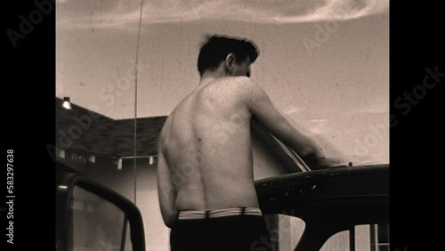 Dad Washes Car 1949 - A young man washes his car while wearing swimming briefs in the late 1940s photo