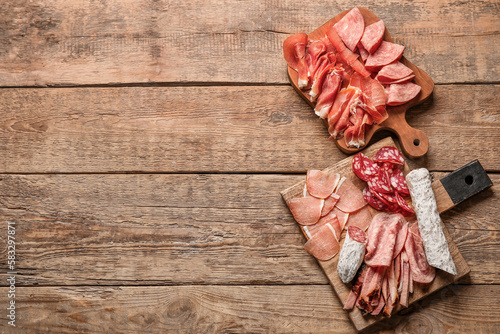 Boards with assortment of tasty deli meats on wooden background