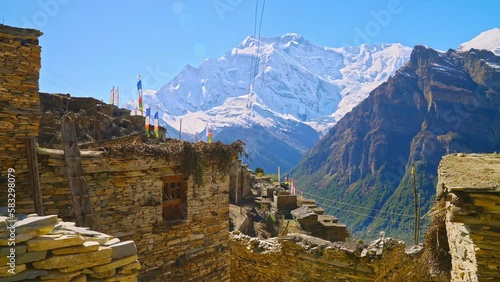 Snow Covered Himalayan mountain peaks by ancient village of rustic stone buildings, Annapurna, Nepal photo
