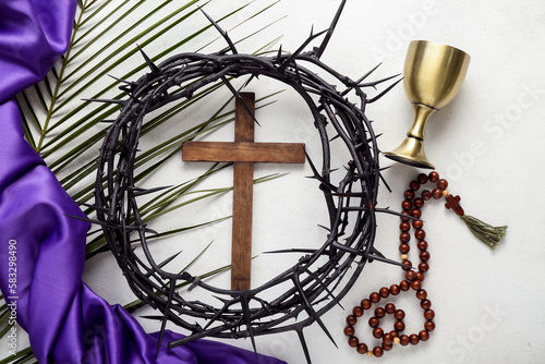 Wooden cross with crown of thorns  prayer beads  wine cup and palm leaf on white background. Good Friday concept