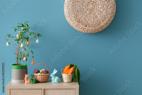 Fototapeta Naklejka Na Ścianę i Meble -  Easter decorations on wooden cabinet near blue wall