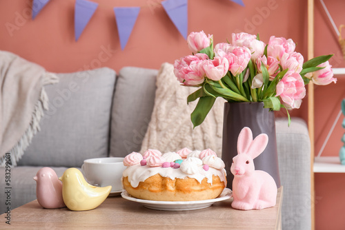 Easter cake  bunny  porcelain quails and vase with tulip flowers on table in living room