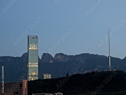 Towering high rises peek over the Loma Larga, a steep hill that divides the cities of Monterrey and San Pedro Garza García, with the Sierra Madre Oriental mountain range in the background photo