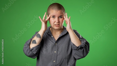 Sick tired headache migraine exhausted displeased non binary gender fluid woman 20s posing isolated on green screen background studio. Put hands on head rub temples