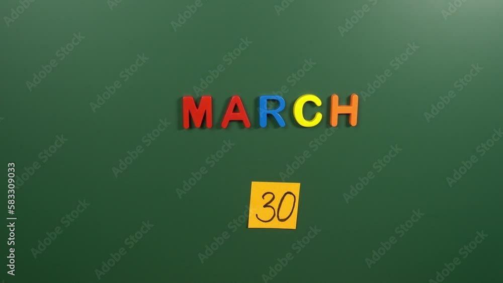 Hand sticking a sticker 30 March calendar day on school board. 30 date of March. Thirtieth day of March. 30th date number. 30 day calendar. Thirty date. National Doctors