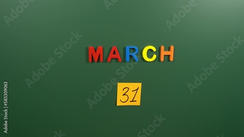 Hand sticking a sticker 31 March calendar day on school board. 31 date of March. Thirty first day of March. 31th date number. 31 day calendar. Thirty one date. International Transgender Visibility photo