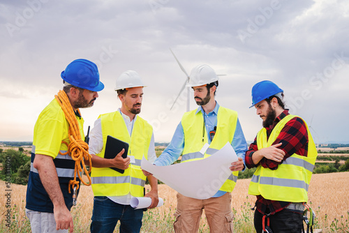 Teamwork of renewable energy architect and engineers reading a blueprint and planning the construction together. Power industry concept. High quality photo