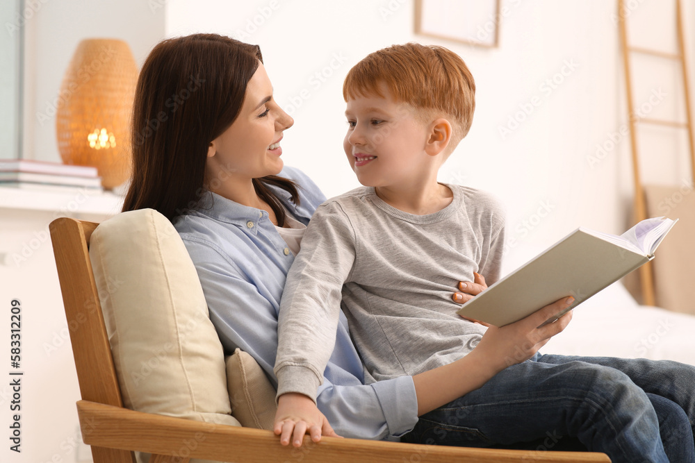 Mother reading book with her child on armchair at home Mother reading book with her child on armchair at home