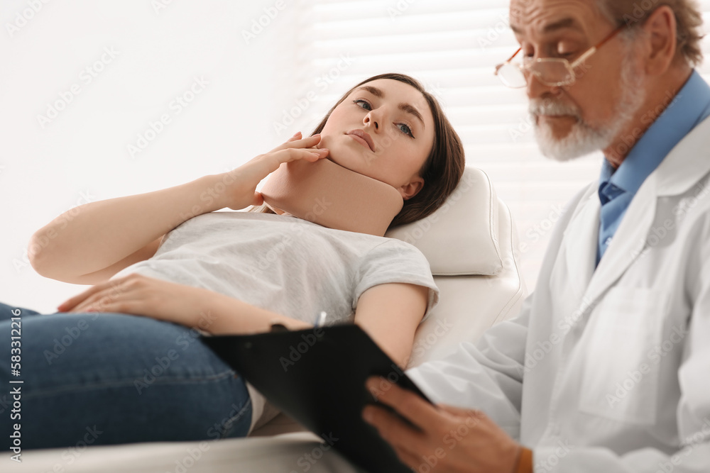 Orthopedist examining patient with injured neck in clinic