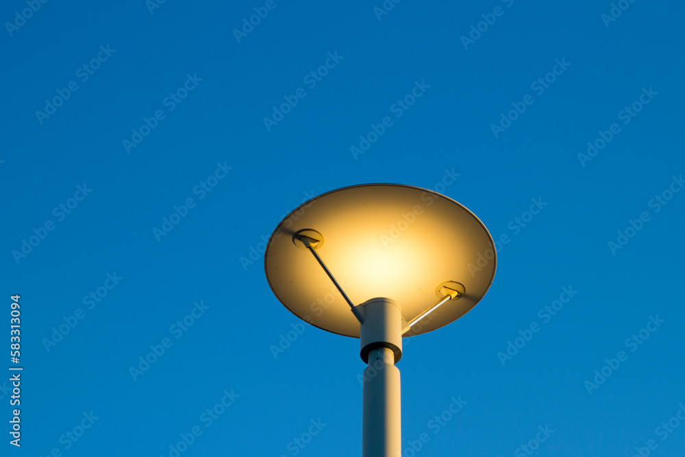 Modern lamppost illuminated with a vibrant blue sky background.
