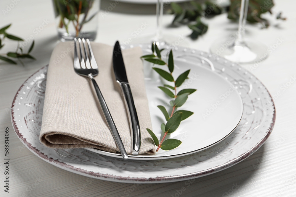 Stylish setting with cutlery and eucalyptus leaves on white wooden table, closeup Stylish setting with cutlery and eucalyptus leaves on white wooden table, closeup