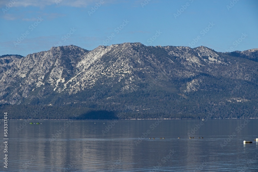 Obraz premium Parasailers and boaters begin their mornings on the peaceful waters of Lake Tahoe in the Sierra Nevada Mountains.