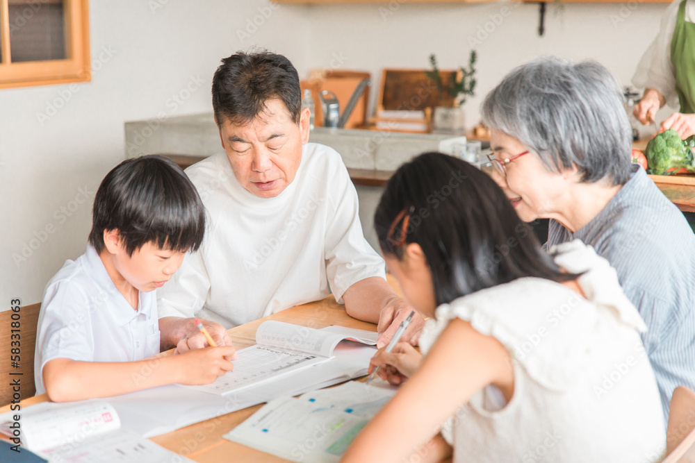 Fototapeta premium 家のダイニングで孫の宿題を教える高齢者夫婦と小学生の子供 