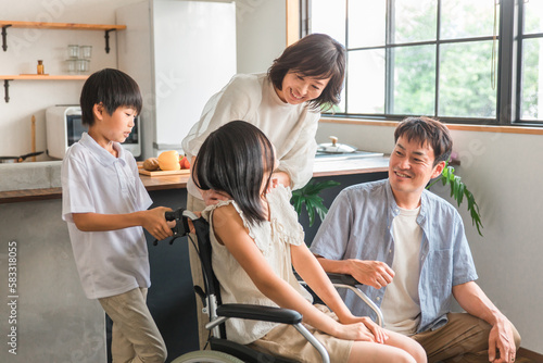 車椅子に乗る女の子と笑顔の家族・ファミリー（車いす体験・退院・バリアフリー） 