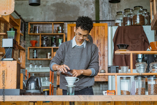 male barista with glasses brewing the coffee using the v60 inside the bar desk