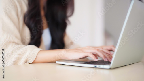 Hand of asian woman typing on computer laptop keyboard at house