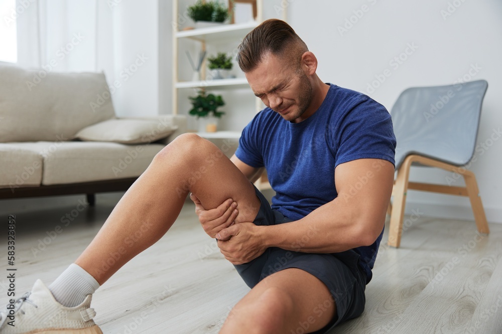 Fototapeta premium Man athlete pain and injury back arm and leg at home, sports injury bodybuilder, concept health and beauty