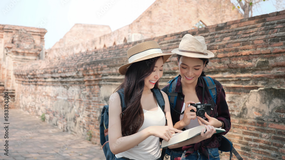 Two Asian women enjoying and writing their journey diary book in the old town. Phra Nakhon Si Ayutthaya, Thailand. Traveling on holidays