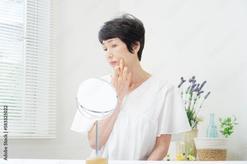 鏡で口元を見て悩んでいる中年女性