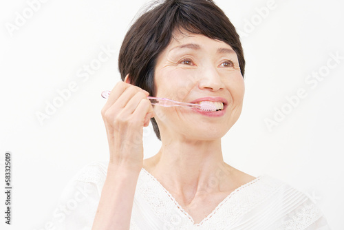 歯磨きをする中年女性 白背景