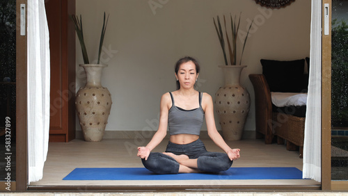 Asian woman in sportswear exercise yoga pose at home in the morning photo