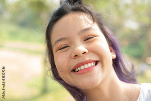 Happy teen girl 11-15 year old. Portrait of beautiful woman smiling with perfect smile and white teeth and looking away at park during sunset. Smile face asian lady girl wear casual cloth.