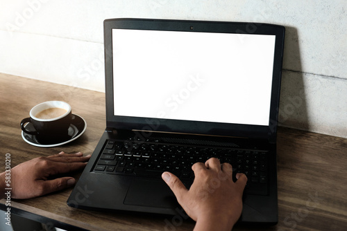 Mockup image of a man using and working on laptop computer with a blank white screen with coffee cup on wooden table