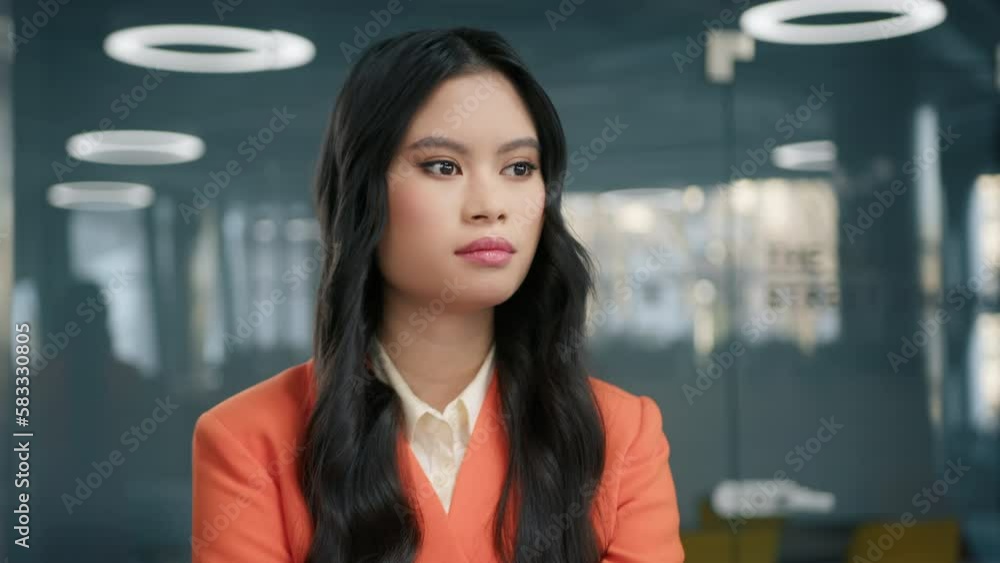 Concentrated professional girl with pretty face hair posing for close up portrait indoors. Confident thoughtful young Asian stylish business woman standing at office attentively listening colleague 4K Concentrated professional girl with pretty face hair posing for close up portrait indoors. Confident thoughtful young Asian stylish business woman standing at office attentively listening colleague 4K