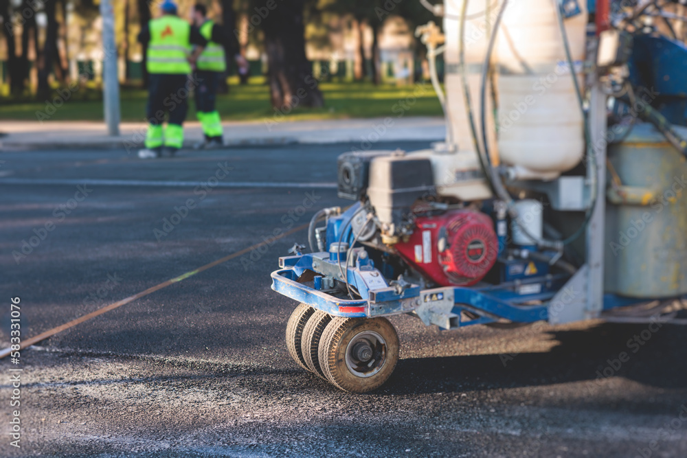Process of making new road surface markings with a line striping machine, workers improve city infrastructure, demarcation marking of pedestrian crossing with a hot melted paint on asphalt pavement Process of making new road surface markings with a line striping machine, workers improve city infrastructure, demarcation marking of pedestrian crossing with a hot melted paint on asphalt pavement