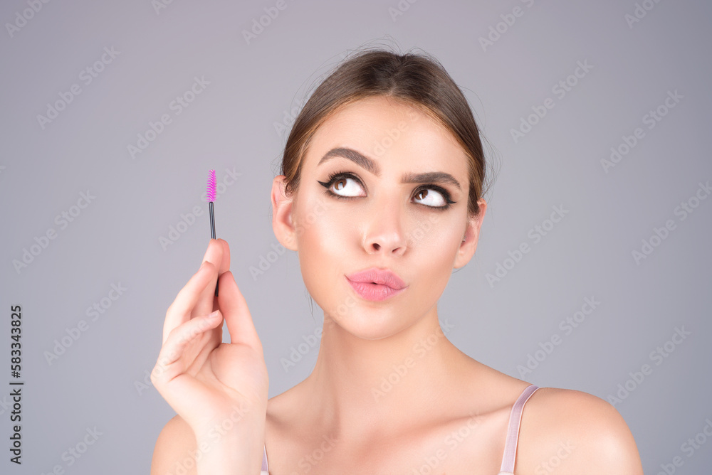Beautiful woman applies brow gel with brows brush to her eyebrow. Studio portrait of young woman doing her eyebrow natural make up. Eyebrows make up concept. Beautiful woman applies brow gel with brows brush to her eyebrow. Studio portrait of young woman doing her eyebrow natural make up. Eyebrows make up concept.