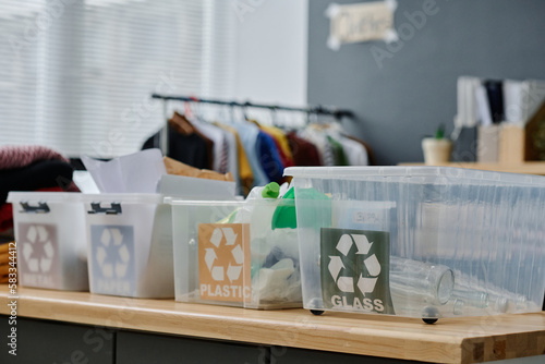 Group of plastic containers for separate litter standing on desk in office of volunteering organization supporting people in need