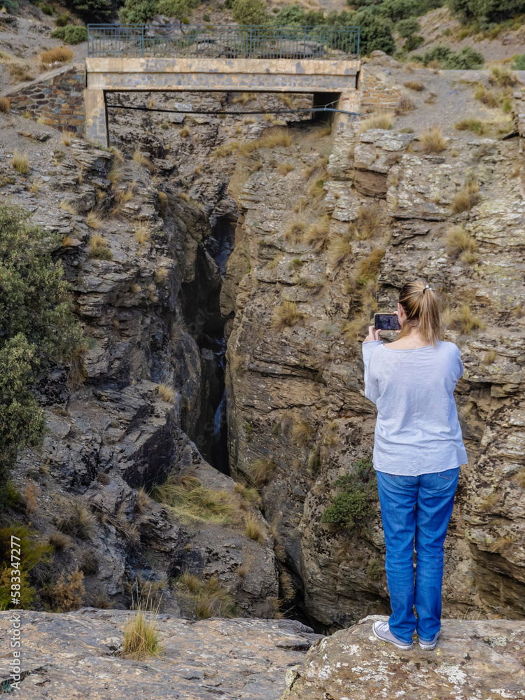Young Caucasian woman dressed in jeans and sweatshirt enjoying the views of the Alpujarra valleys of Granada