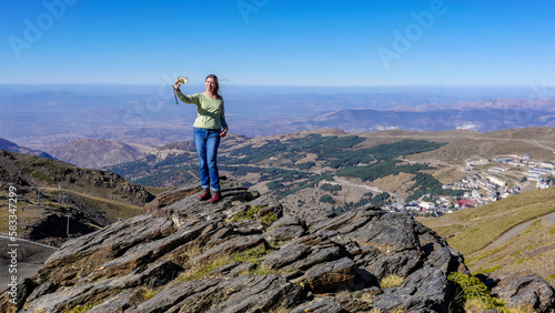 Young Caucasian woman dressed in jeans and sweatshirt enjoying the views of the Alpujarra valleys of Granada photo