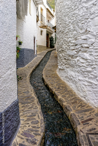 street of a town in the Alpujarra of Granada with water running through a canal in the center of the road