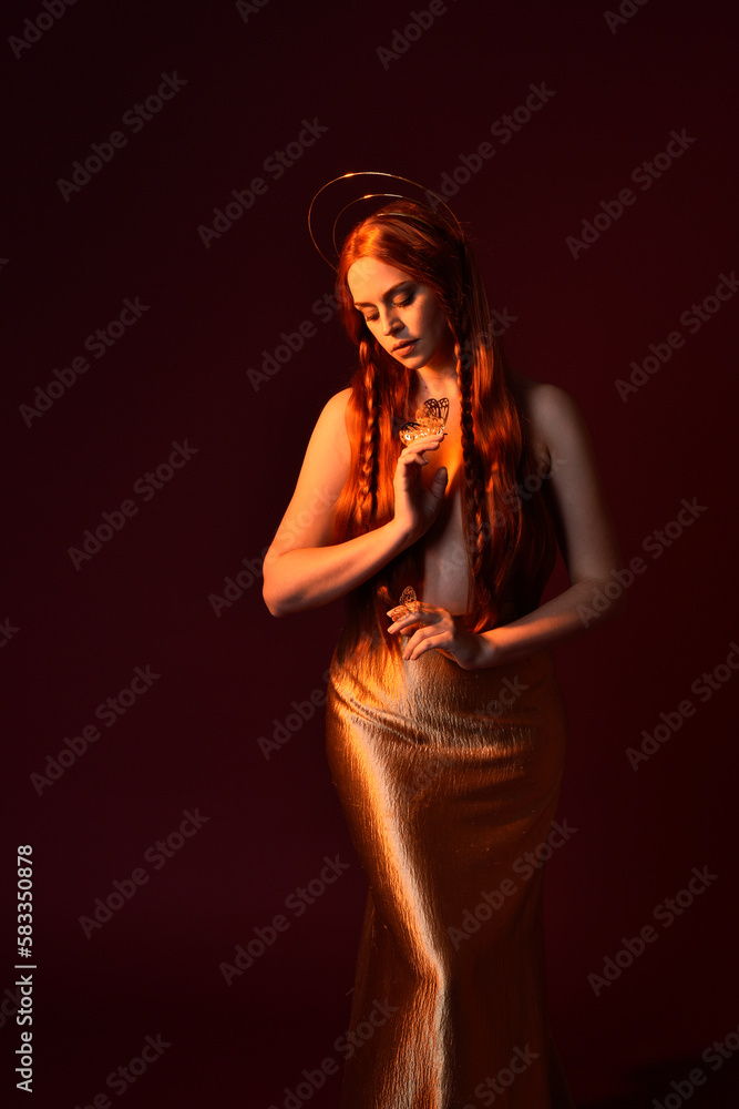 Close up fantasy portrait of beautiful woman model with red hair, goddess silk robes & gold crown. Posing with gestural hands reaching out, isolated on dark red studio background Close up fantasy portrait of beautiful woman model with red hair, goddess silk robes & gold crown. Posing with gestural hands reaching out, isolated on dark red studio background